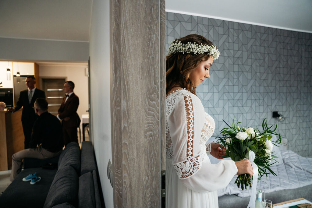 Panna młoda przy oknie podczas przygotowań — naturalna fotografia ślubna